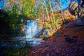 Hungarian Falls waterfall with prism of color around it hinting at a rainbow and falls leaves against the forested