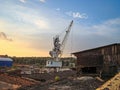 Image of an industrial or construction site with a retracted crane, two worn structures cabin and storage facility Royalty Free Stock Photo