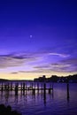 Infrared of empty docks and silhouette of a city with a crescent moon and purple sky and water with sunrise white Royalty Free Stock Photo