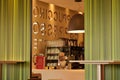 Image of interior serving counter at fast food restaurant with view of coffee glasses, machines and decorative wall