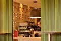 Image of interior serving counter with female worker at fast food with view of coffee glasses, machines and decorative wall