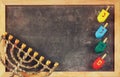 image of jewish holiday Hanukkah with menorah (traditional Candelabra) and wooden colorful dreidels (spinning top) over chalkboard Royalty Free Stock Photo