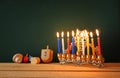 low key image of jewish holiday Hanukkah with menorah (traditional Candelabra) and wooden dreidels spinning top over chalkboard Royalty Free Stock Photo