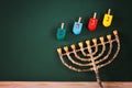 image of jewish holiday Hanukkah with menorah (traditional Candelabra) and wooden colorful dreidels (spinning top) over chalkboard Royalty Free Stock Photo