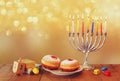 image of jewish holiday Hanukkah with menorah (traditional Candelabra), donuts and wooden dreidels (spinning top)