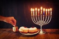 image of jewish holiday Hanukkah with menorah (traditional Candelabra), donuts and wooden dreidels (spinning top). retro filtered Royalty Free Stock Photo