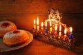 Image of jewish holiday Hanukkah with menorah (traditional Candelabra), donuts and wooden dreidels (spinning top). Royalty Free Stock Photo