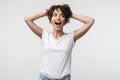 Image of joyous woman with short hair in basic t-shirt laughing and grabbing her head