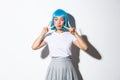 Image of kawaii asian woman in blue shirt wig, shows peace gesture and pout. Girl in halloween costume enjoys party