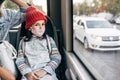 Image of the kid wears a red winter hat in protective face mask going to school by bus during coronavirus with mother. A little Royalty Free Stock Photo