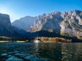 Image of the Koenigssee with the chapel of st bartholomew and a tourist boat. In the background the illuminated mountain formation