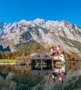 Image of the Koenigssee with a water reflection of the chapel of st bartholomew and a tourist boat. In the background the