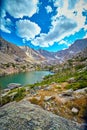 Lake in rocky mountains with lichen rock in foreground