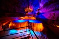 Large underground waterfall in cave on tour path with orange and blue lights Royalty Free Stock Photo
