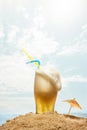 Image of light foamy beer, glass standing into sand over sea and sky background. Summertime chill. Overflowing