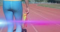 Image of light moving over midsection of woman holding running shoes walking on running track