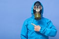 Image of liquidating agent looking directly at camera, making gesture, showing direction with forefinger, being in gas mask and Royalty Free Stock Photo