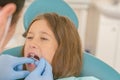 Image of little girl having her teeth checked by doctor. Little girl at the dentist examining a lose tooth with a dental mirror