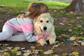 Image of little girl hugging white puppy dog laying on park ground