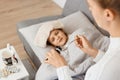 Image of little unhealthy girl lying on cough, mother taking care of her sick daughter, mommy treating her kid with towel on Royalty Free Stock Photo