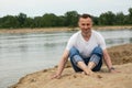 The image lonely positive man sitting on the beach river Royalty Free Stock Photo