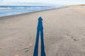 Image of a long shadow of a person on a wide sandy beach