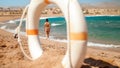 Image of looking through plastic white life saving ring on sexy young owman in small black bikini walking on the beach. Royalty Free Stock Photo