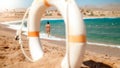 Image of looking through plastic white life saving ring on sexy young owman in small black bikini walking on the beach. Royalty Free Stock Photo