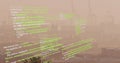 Image of looping computer language over fog covered modern city against sky