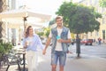 Image of lovely happy couple in summer clothes smiling and holding hands together while walking through city street Royalty Free Stock Photo