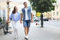 Image of lovely happy couple in summer clothes smiling and holding hands together while walking through city street Royalty Free Stock Photo