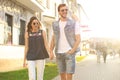 Image of lovely happy couple in summer clothes smiling and holding hands together while walking through city street Royalty Free Stock Photo