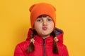 Image of lovely little female kid with rounded lips looking with surprised expression, posing isolated over yellow background,