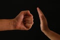 Image of male fist and female hand showing STOP. Domestic violence concept against women.