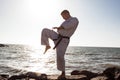 Image of male karate fighter posing on stones sea background Royalty Free Stock Photo