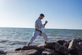 Image of male karate fighter posing on stones sea background Royalty Free Stock Photo