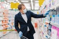 Image of man consumer buys detergent in shopping mall, takes bottle of washing gel in cart, chooses household products, cares