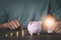 image of man hand holding light bulb with pink piggy bank for account save money. Royalty Free Stock Photo