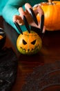Image of man`s hands with pumpkin jack sitting at wooden table
