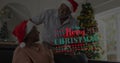 Image of merry christmas text over senior african american couple wearing santa hats Royalty Free Stock Photo