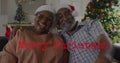 Image of merry christmas text over senior african american couple wearing santa hats Royalty Free Stock Photo