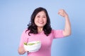 Image of middle aged Asian woman eating salad on blue background Royalty Free Stock Photo