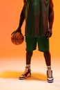 Image of midsection of african american basketball player with basketball on neon orange background