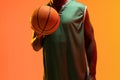 Image of midsection of african american basketball player with basketball on neon orange background