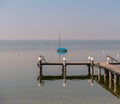 Image of mothballed sailing boat on a lake with wodden private pier in the foreground Royalty Free Stock Photo