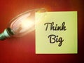 Image with motivational quotes, think big on sticky note with bright shinning bulb and red color background