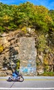 Motorcycle driving on road from side past cliffs and stone wall patch with blue graffiti