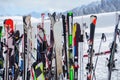 Image of multi-colored skis and snowboards in snow at winter resort in afternoon.