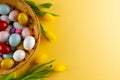 Image of multi coloured easter eggs in basket with yellow tulips and copy space on yellow background Royalty Free Stock Photo