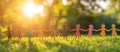 An image of multicolored paper cutouts, hand in hand, standing on a lush green lawn under the dappled sunlight from the Royalty Free Stock Photo